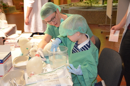 Medizinstudenten zeigen Kindern, wie ein Gips angelegt wird. 