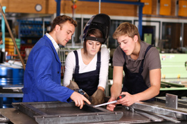 Ausbilder in der Werkstatt vermittelt Auszubildender und Auszubildendem Wissen