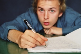 Schüler mit Stift in der Hand, wirkt gelangweilt 