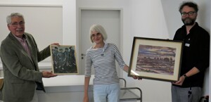 Bild: Friedhelm Halldorn (l.) aus Lemförde schenkte die Bilder der Gedenkstätte Esterwegen, die von Dr. Sebastian Weitkamp, wiss. Mitarbeiter der Stiftung Gedenkstätte Esterwegen, und Dr. Andrea Kaltofen, Geschäftsführerin der Stiftung Gedenkstätte Esterwegen (Mitte), entgegen genommen wurden. Es handelt sich um ein Aquarell, das eine Moorlandschaft zeigt, und ein Bild der Moorsoldaten (rechts; Öl auf Spanplatte). (Foto: Gedenkstätte Esterwegen)